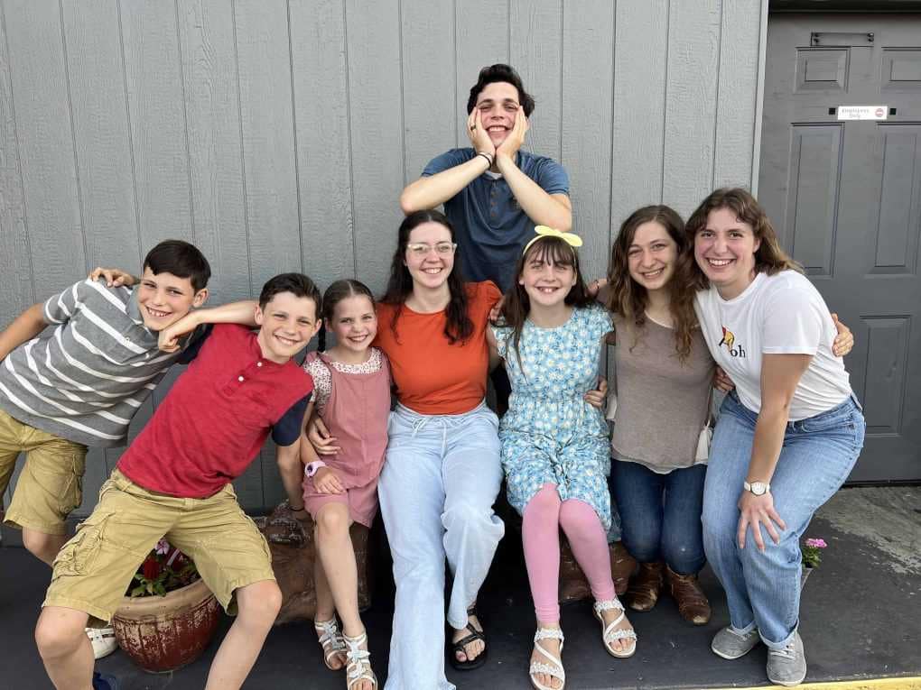 large family of siblings outside of a restaurant