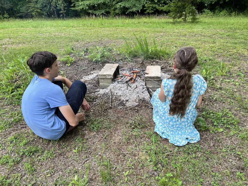 two siblings roasting hot dogs