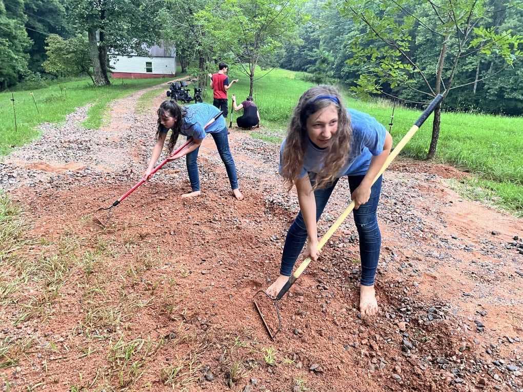 family raking gravel onto driveway