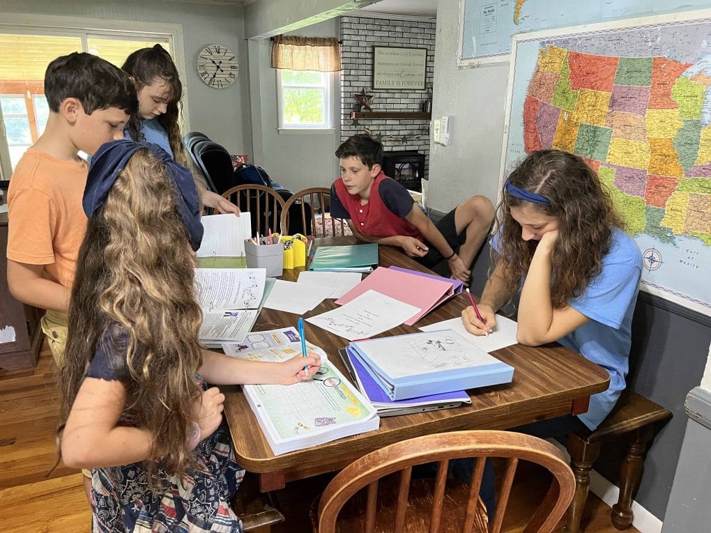 children homeschooling around the table