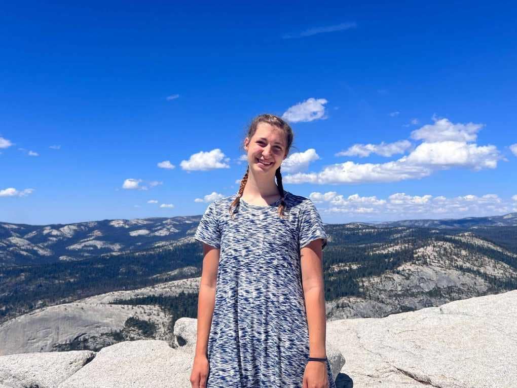 girl standing on top of Half Dome