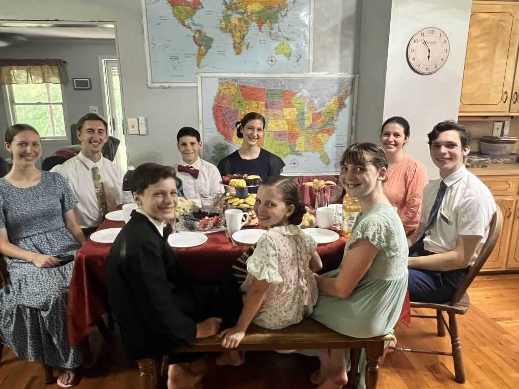 9 siblings sitting around the table in fancy clothes