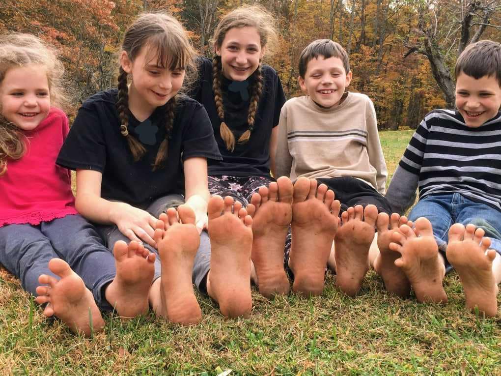 5 kids sitting barefoot next to each other in fall