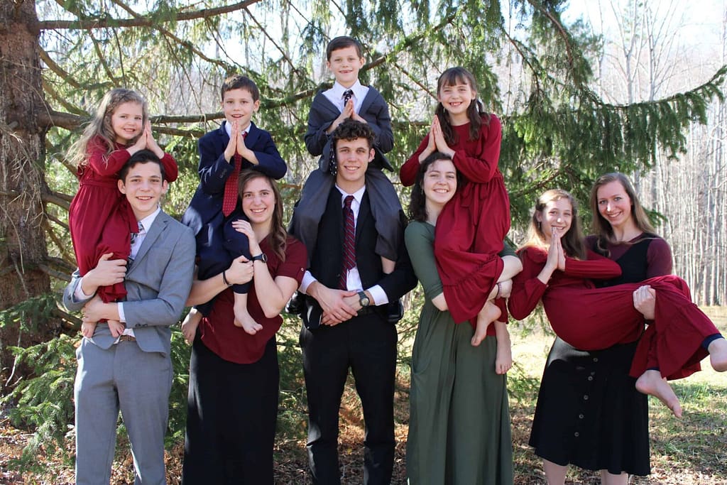 10 siblings doing shoulder angel poses for a Christmas picture