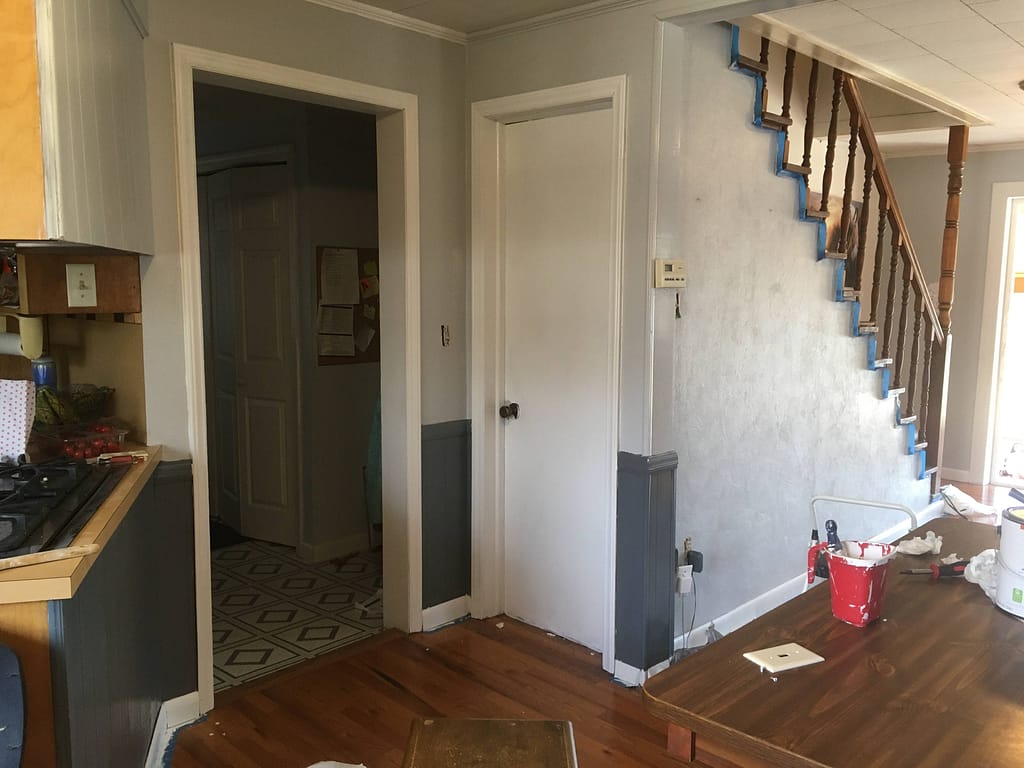 basement door painted white with new black door knob and staircase wall painted gray