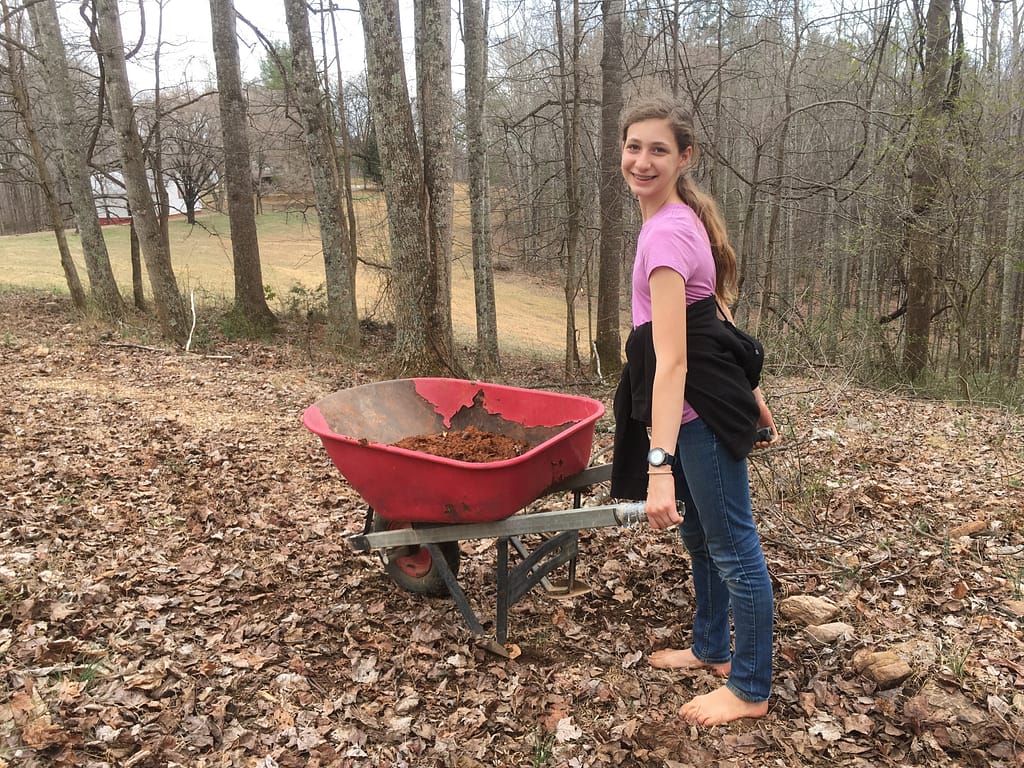 12 year old with t-shirt and jeans carrying a wheelbarrow