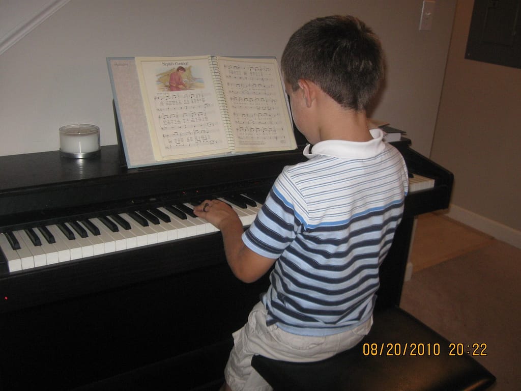 A 6 year old boy child plays a digital piano.