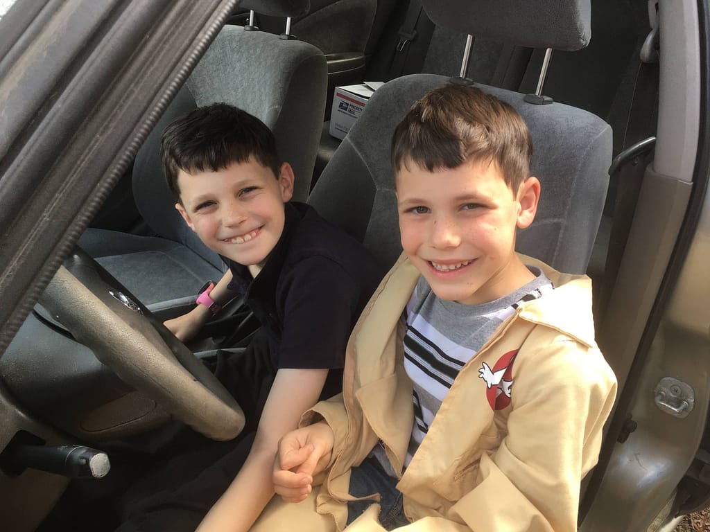 Two little boys sitting in a Nissan car.