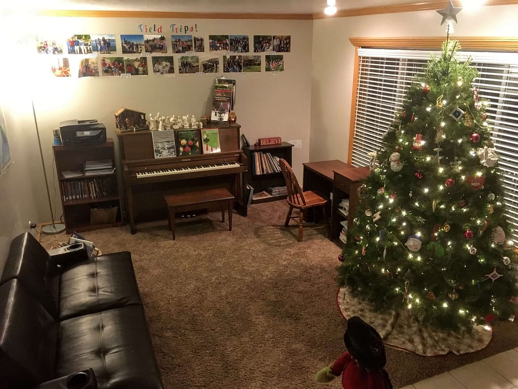 A front room showing a piano, student desk, and Christmas tree all ready for Christmas.