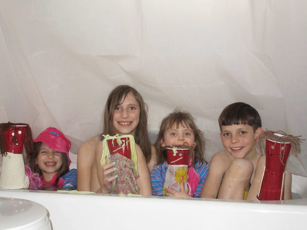 4 kids doing Vietnamese water puppetry in the bathtub