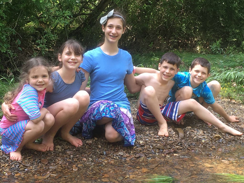 5 kids hugging at the creek