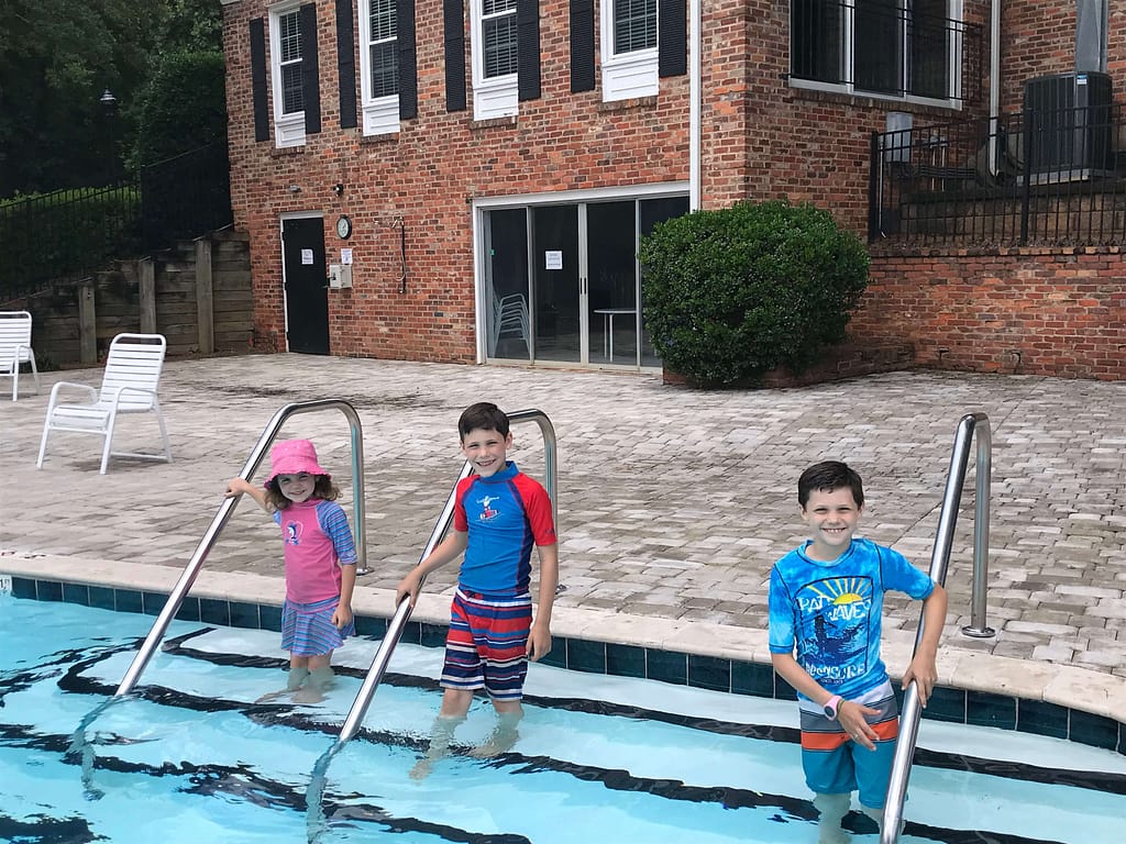 3 kids at a swimming pool on the stairs