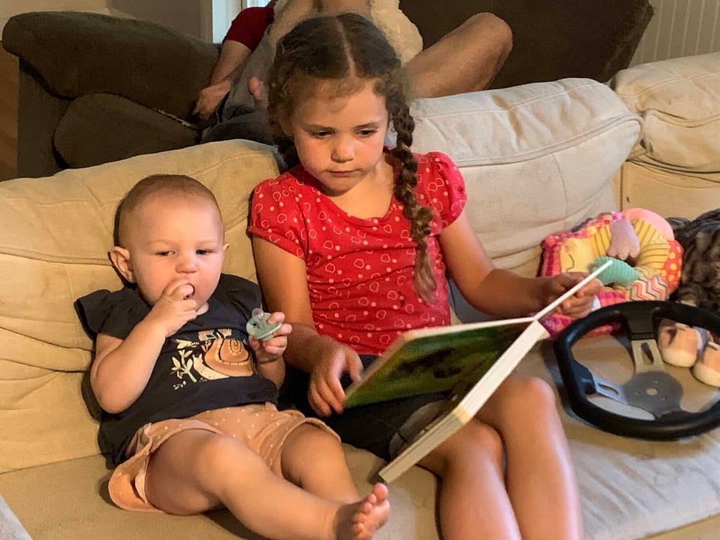 6 year old reading to 10 month old on the couch