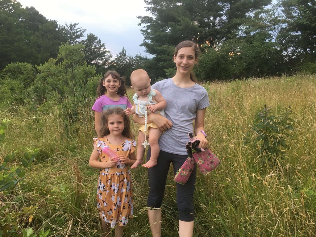 4 kids standing in tall field of grass