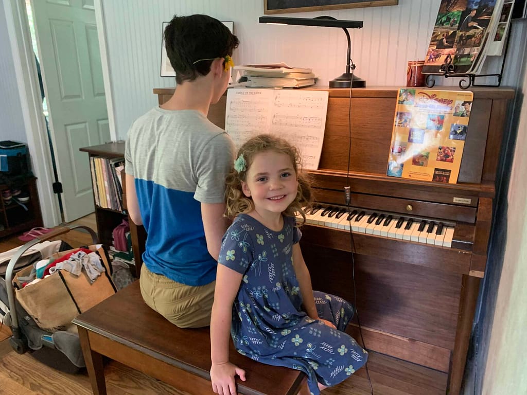 brother and little sister playing the piano together