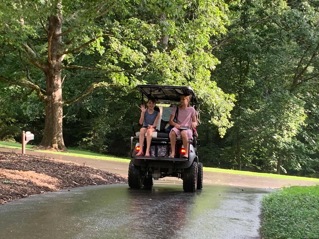 kids riding in a golf cart on a rainy summer day