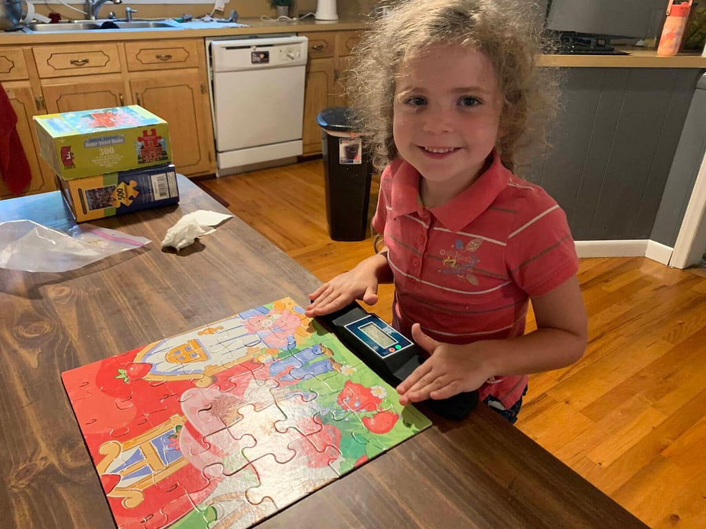 6 year old girl times herself as she does a puzzle