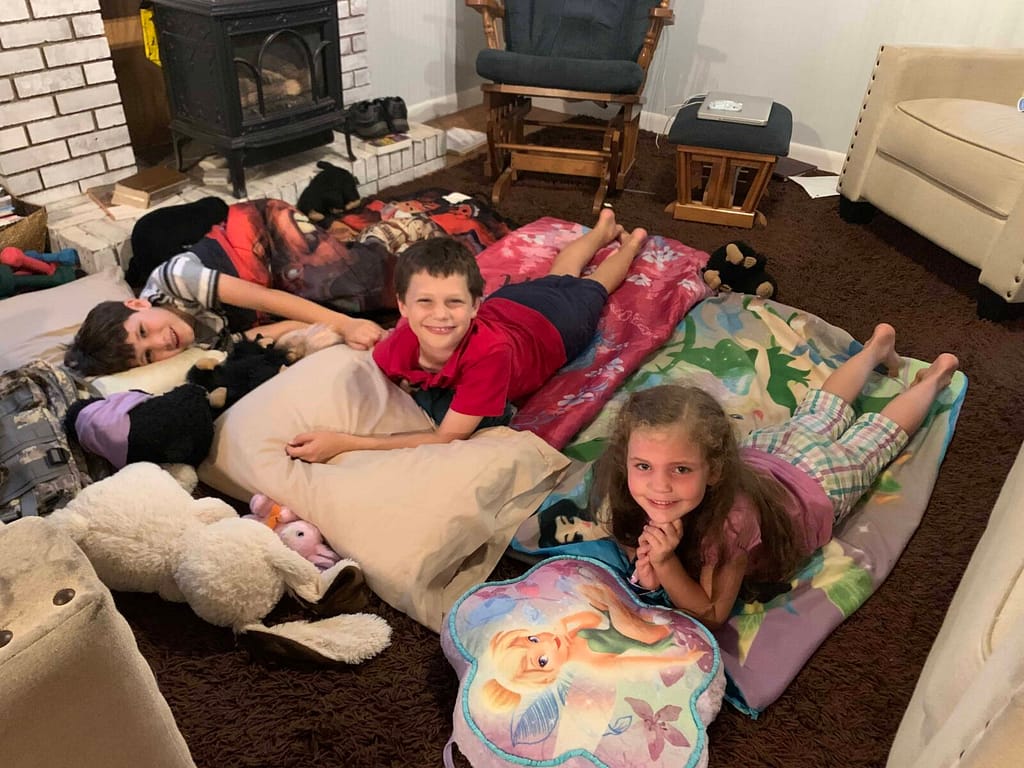 3 kids sleeping in sleeping bags on the living room floor
