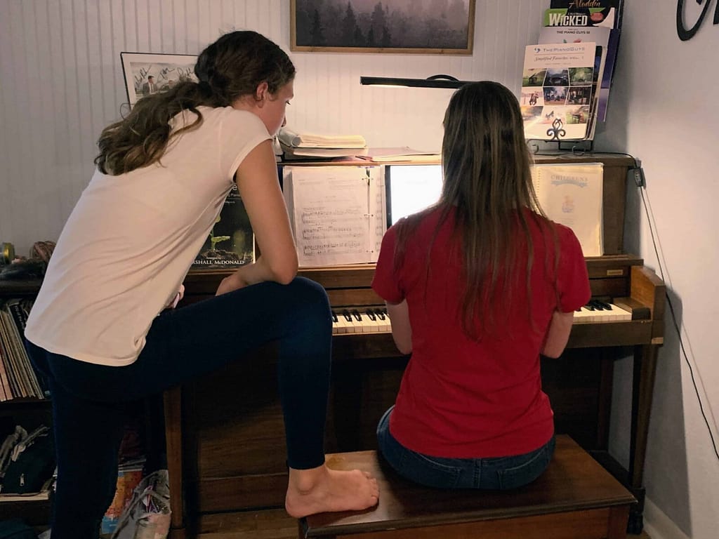 two sisters playing the piano and singing together