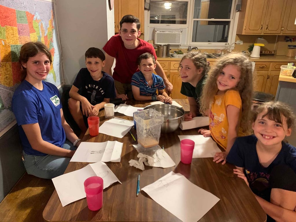 kids drawing silly people around the table