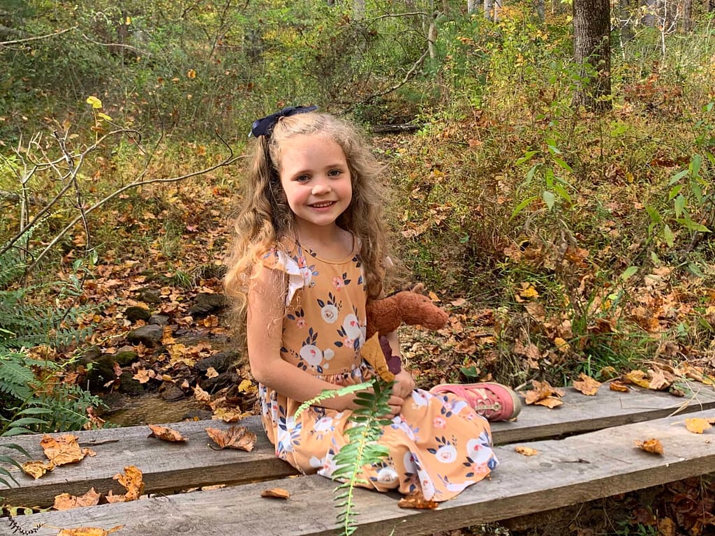 6 year old sitting on wood bridge over small stream in the fall