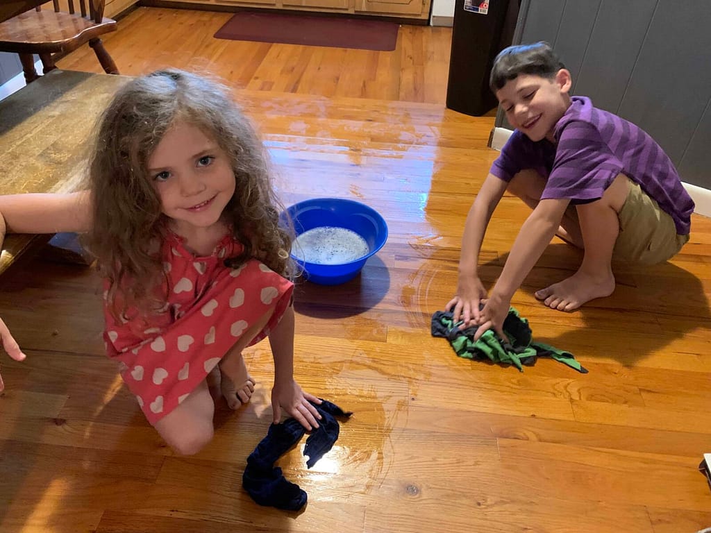 two kids scrubbing the wood floors
