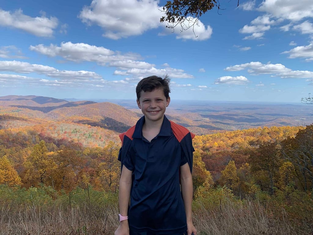 10 year old with blue ridge mountains behind him in fall
