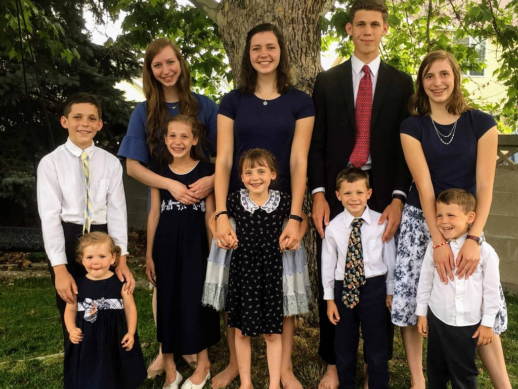 10 Holladay children each standing with their buddies, dressed in navy blue Sunday clothes