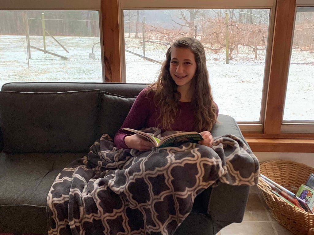 girl sitting on the couch reading while it snows