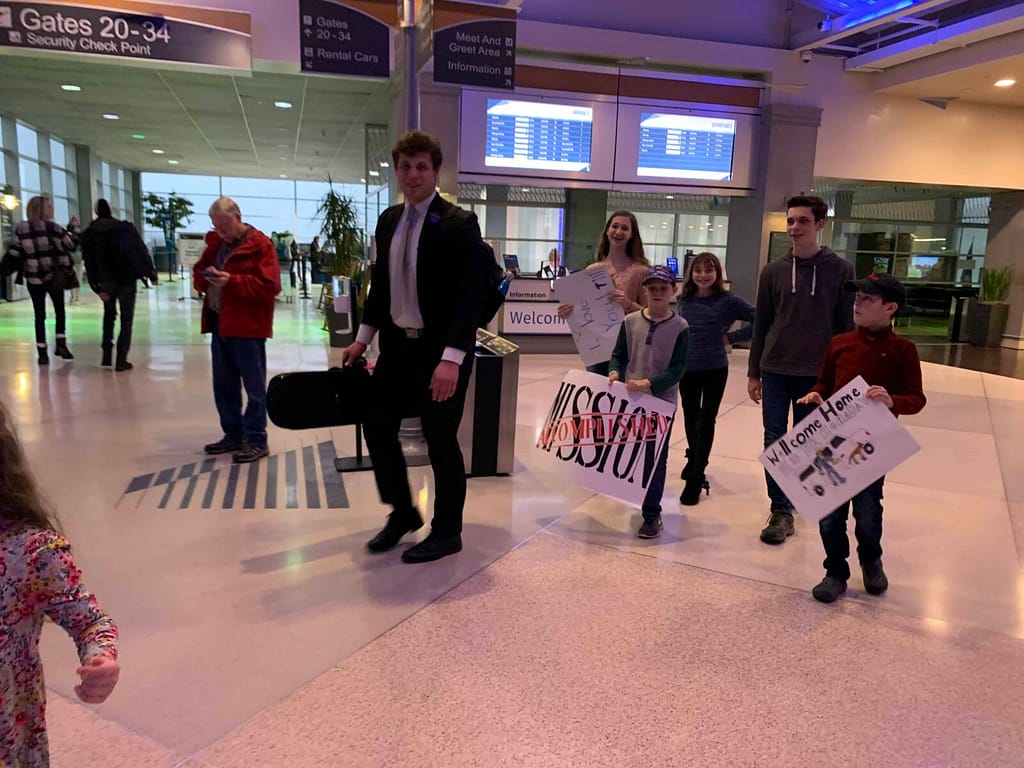 brother and siblings carrying signs at the airport