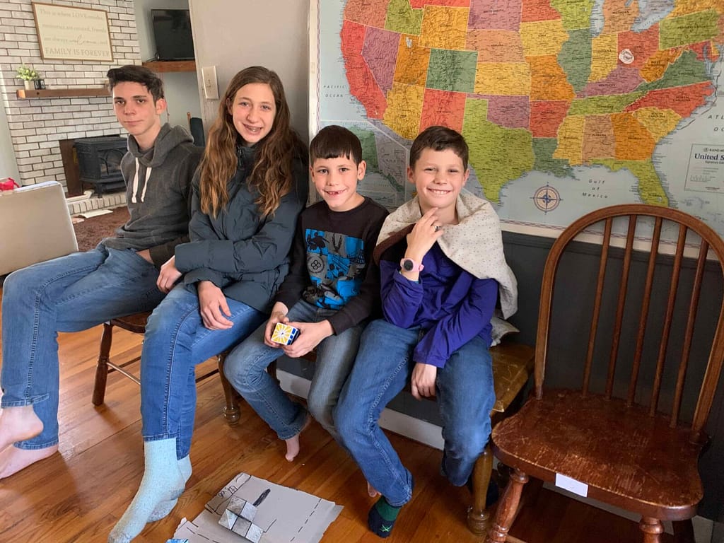 4 siblings sitting on a bench in the house