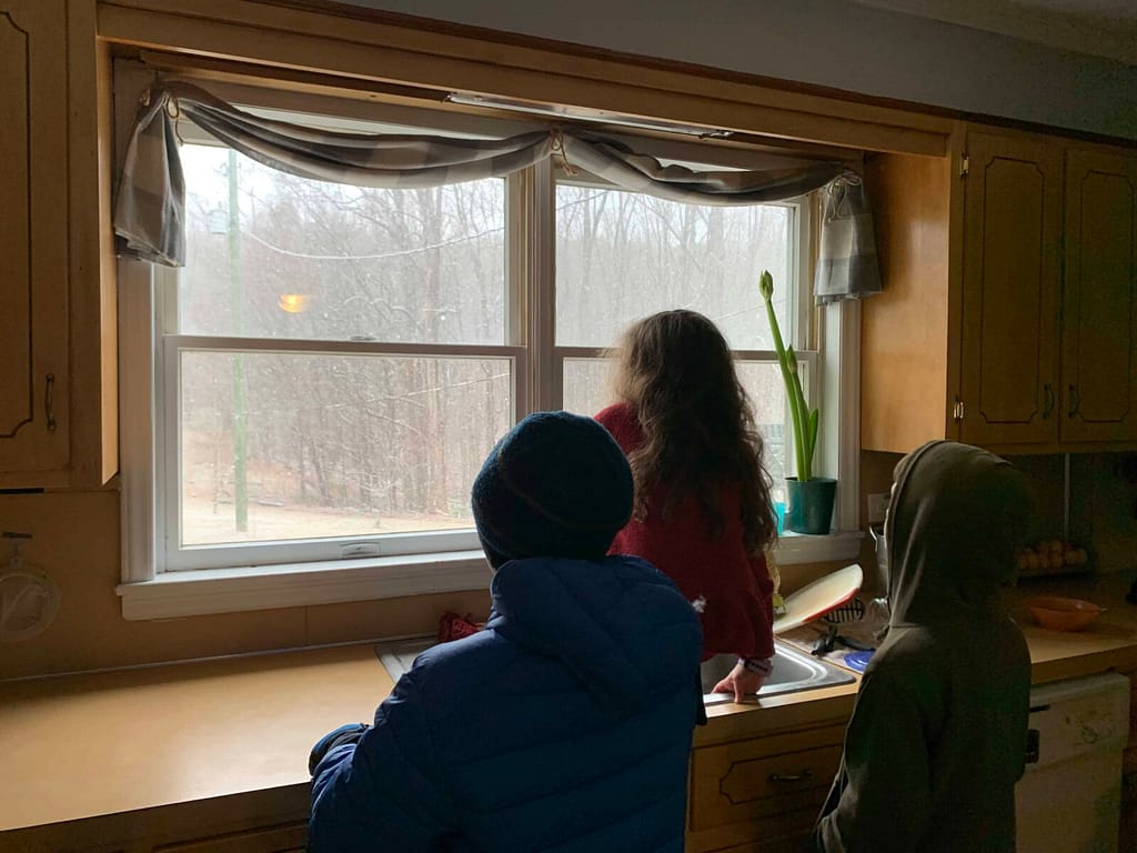3 kids watching it snow out the window
