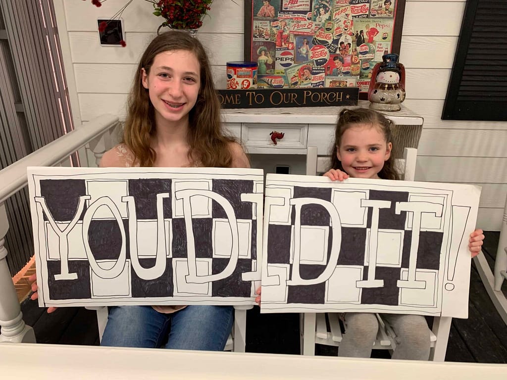 two sisters holding a you did it sign