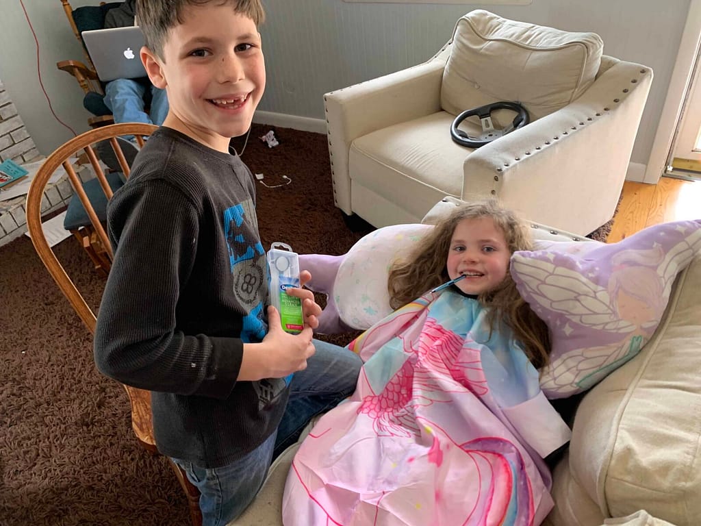 boy playing dentist on little girl