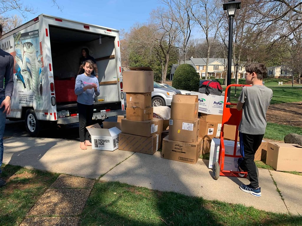 kids with boxes outside of uhaul, ready to pack them