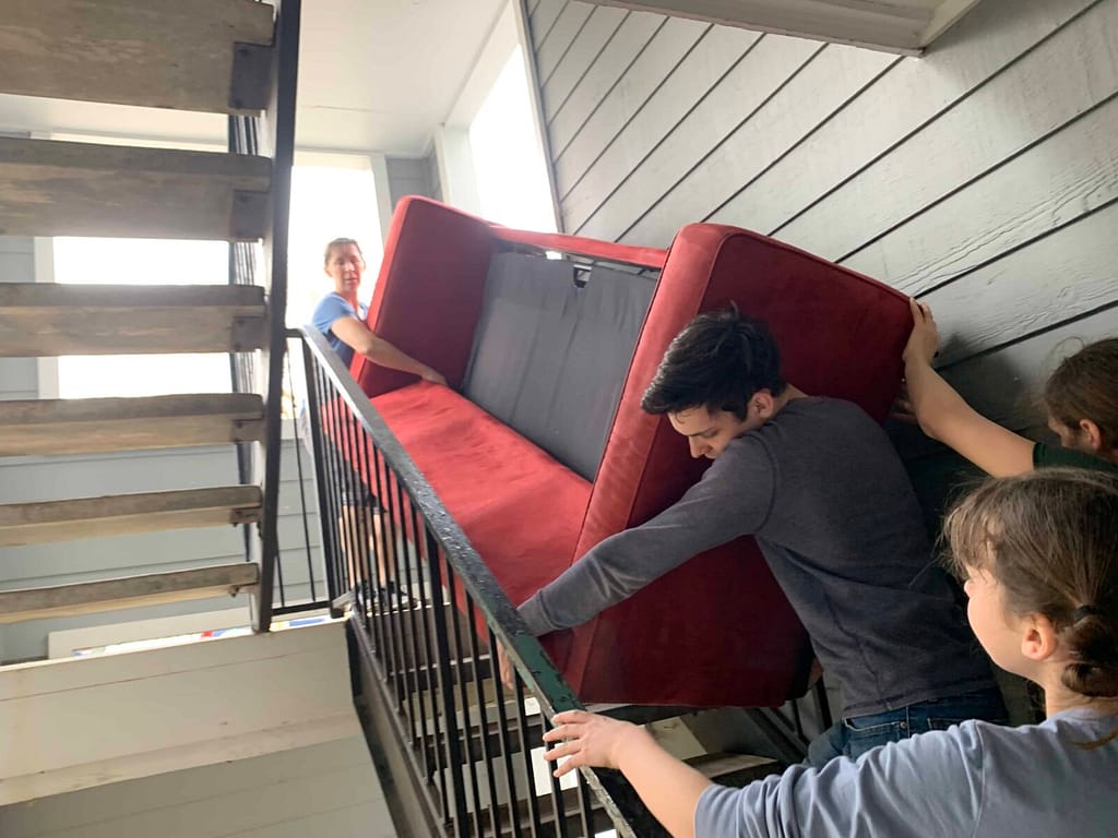 people moving red couch up the stairs