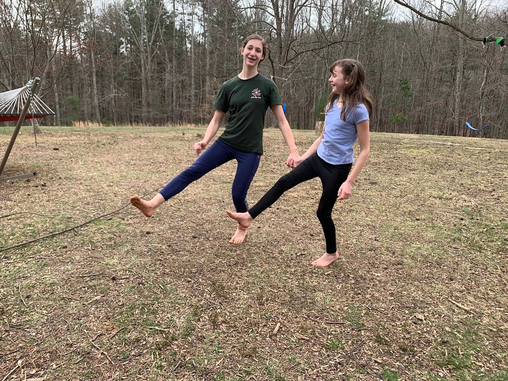 2 sisters doing a dance in a big yard in winter