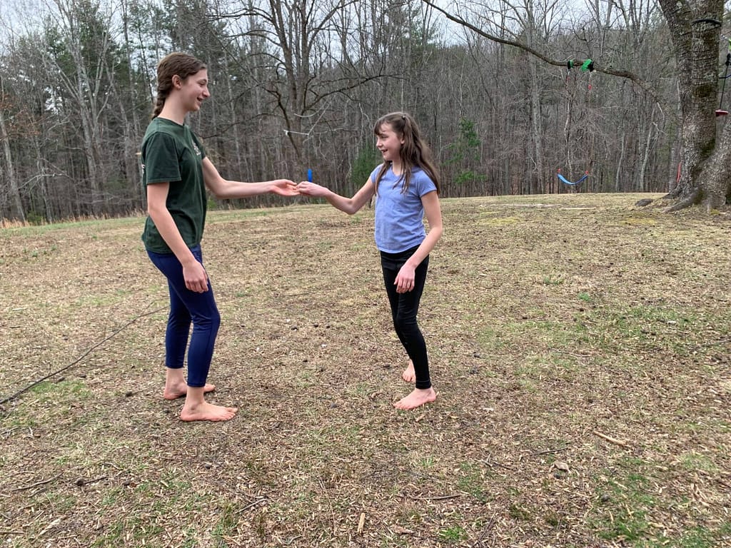 2 sisters doing a dance in a big yard in winter