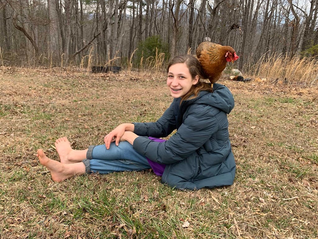 13 year old girl on the grass in winter with a chicken on her shoulder