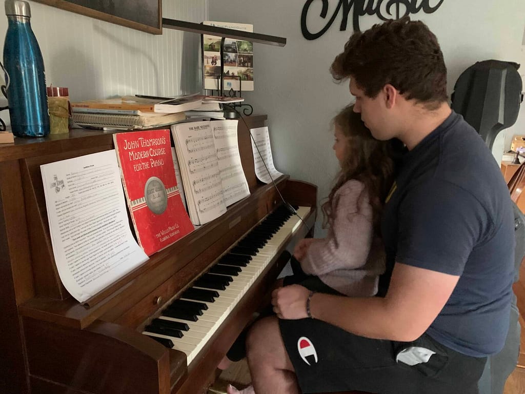 brother with little sister on his lap at the piano