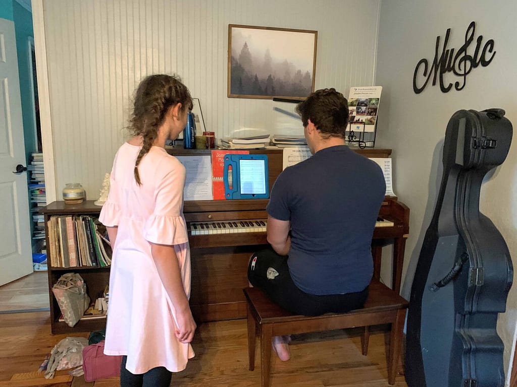 brother and sister practicing at the piano