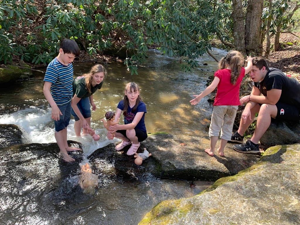 kids playing in a creek with dolls