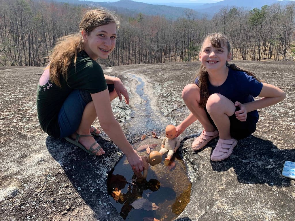 two sisters playing with dolls in a puddle on Stone Mountain