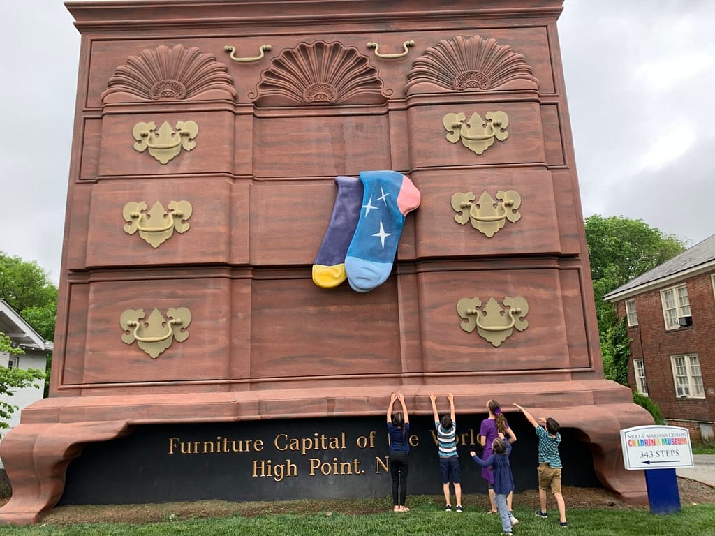 kids standing in front of the biggest dresser in the world