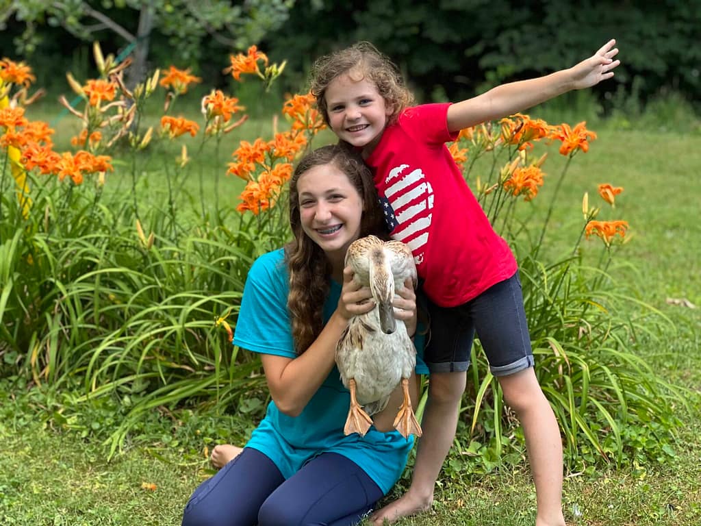 2 sisters holding a duck and smiling