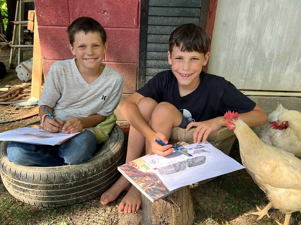 boy sitting in a tire and boy sitting in a barrel and sketching