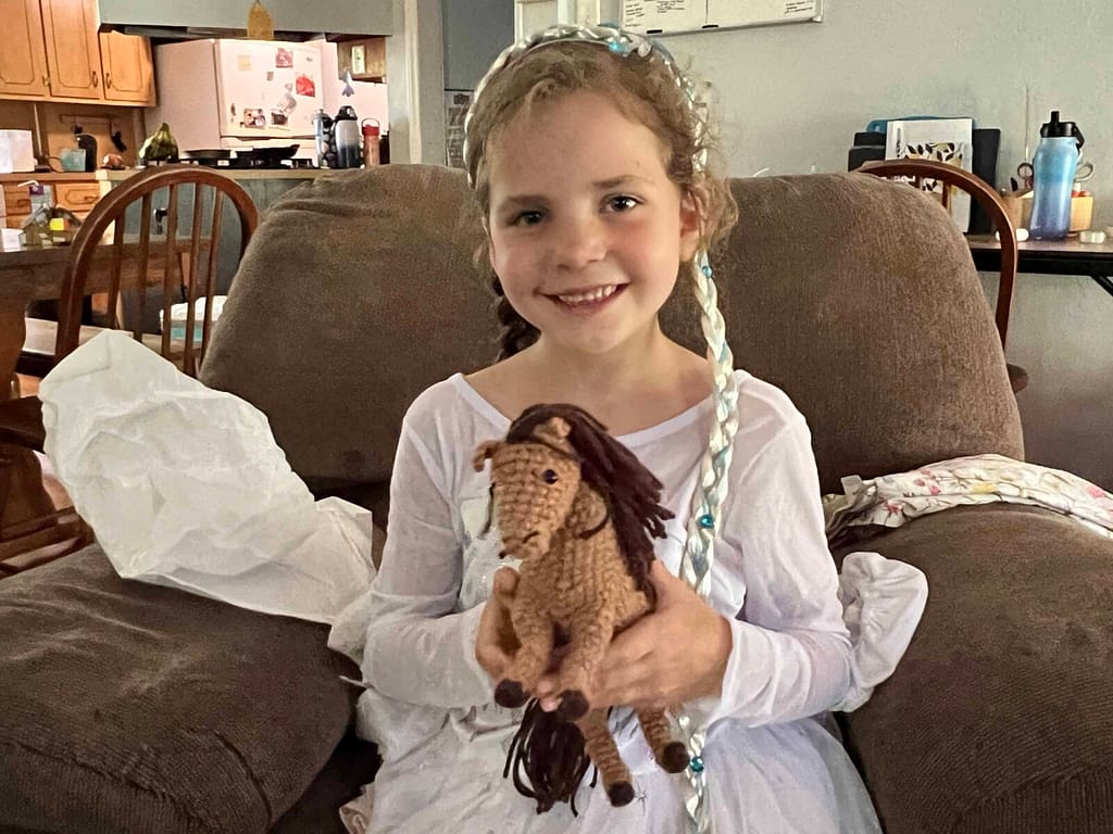 girl holding a crochted horse.