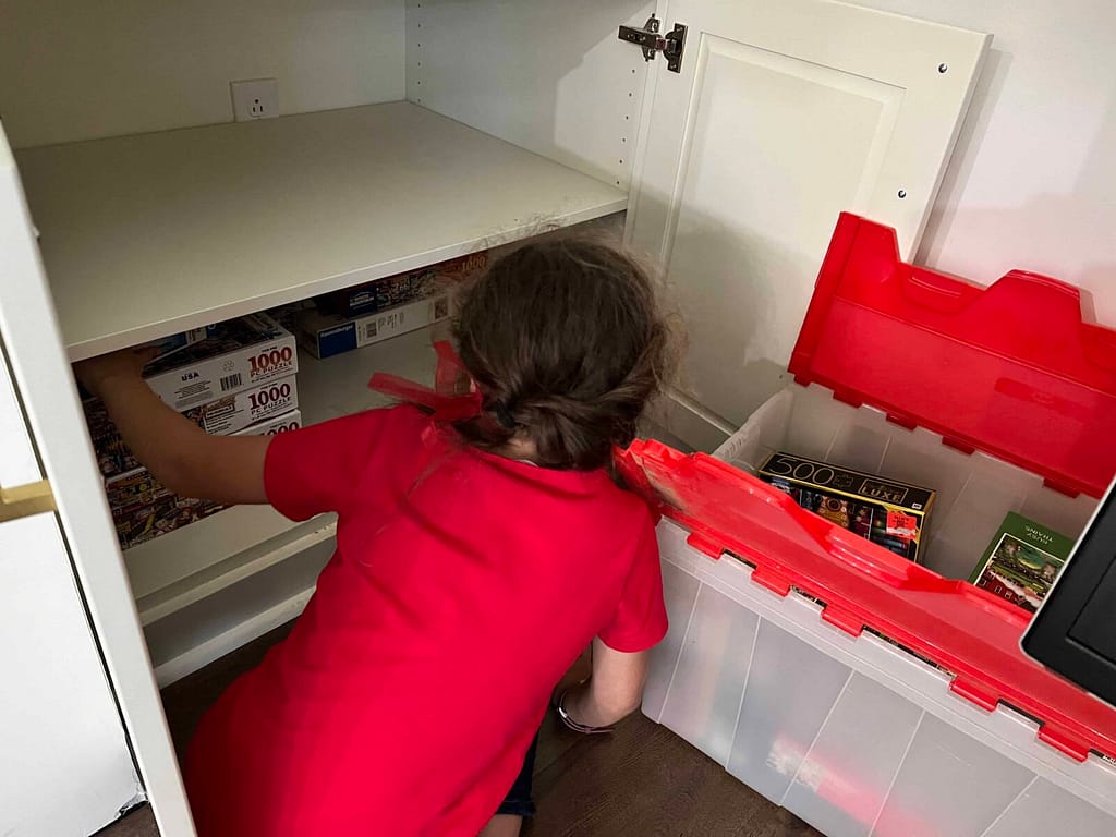 girl organizing puzzles in a cabinet.