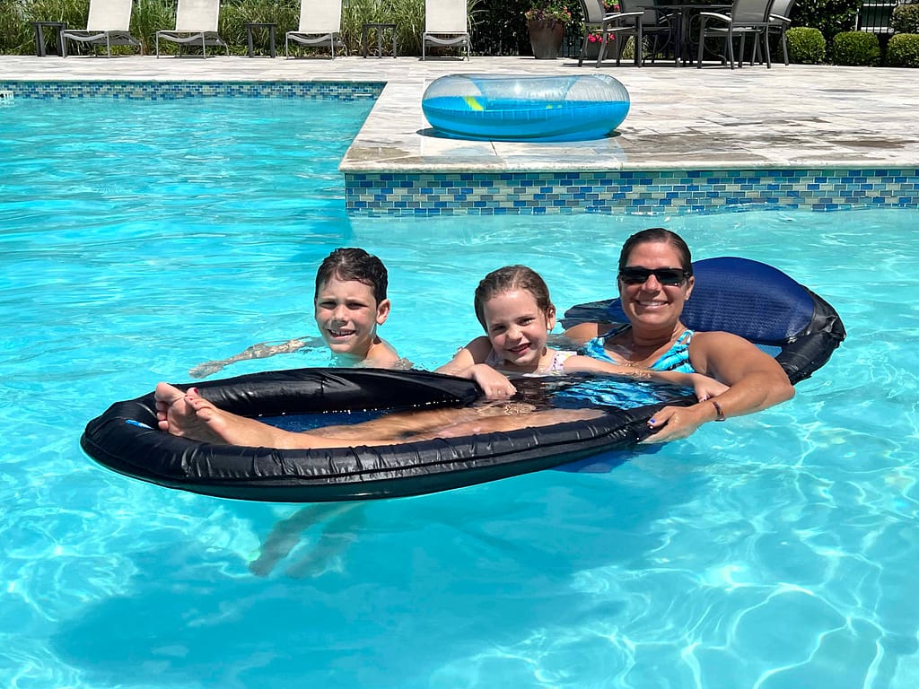 aunt and niece and nephew on a floatie in the pool