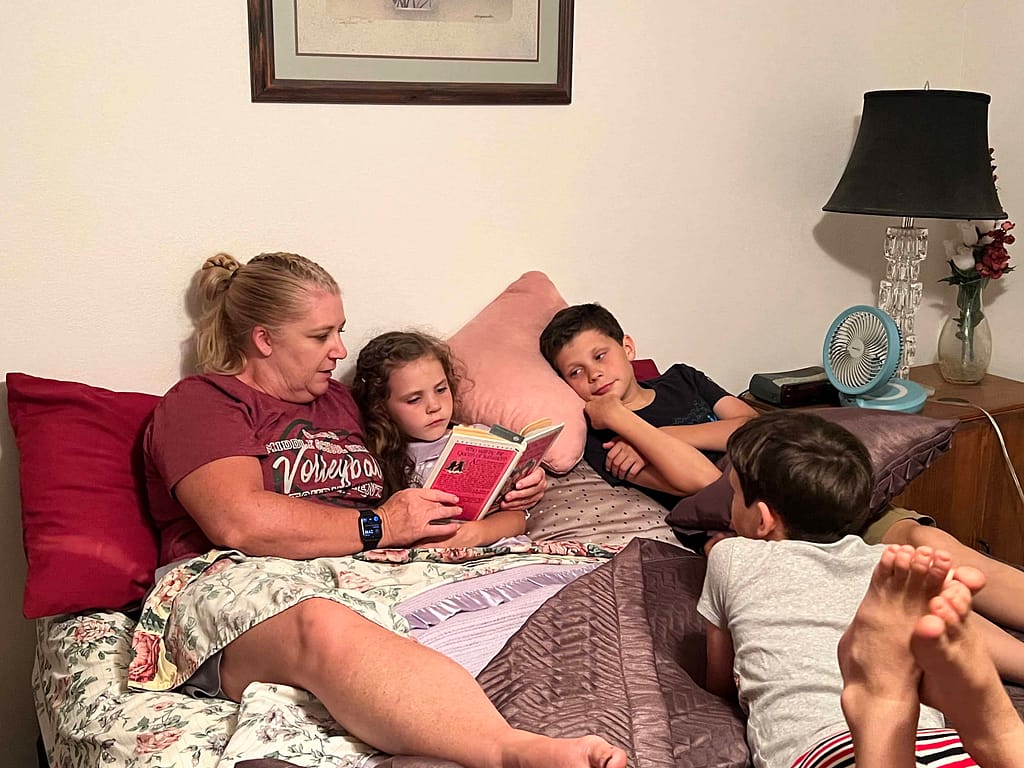 an aunt reading a book to 3 children